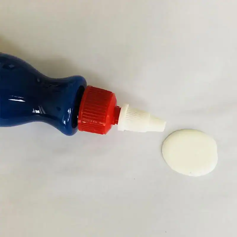 Car paint scratch remover bottle with applicator tip and a dab of product on surface.